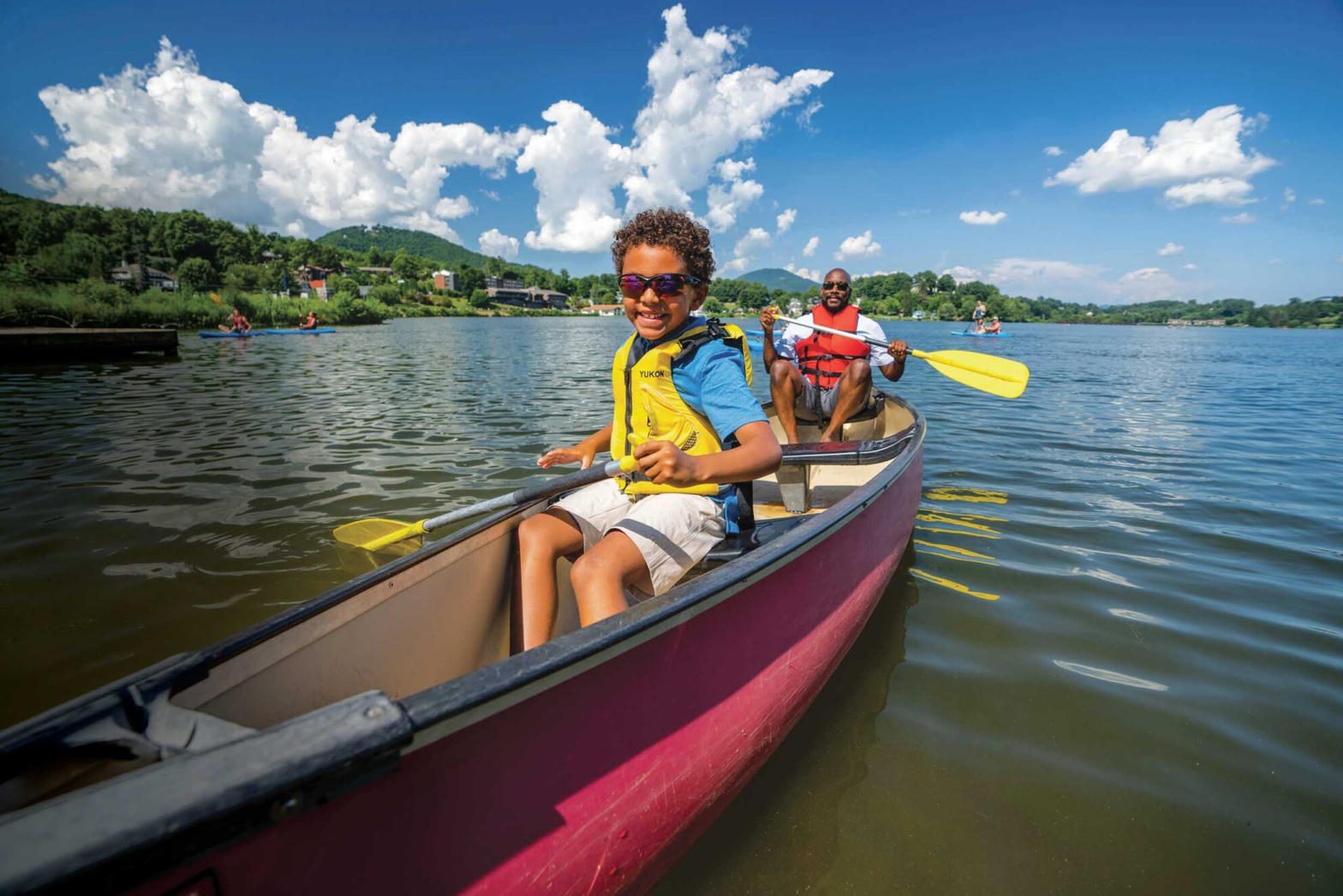 A cub scout and a parent paddling a canoe