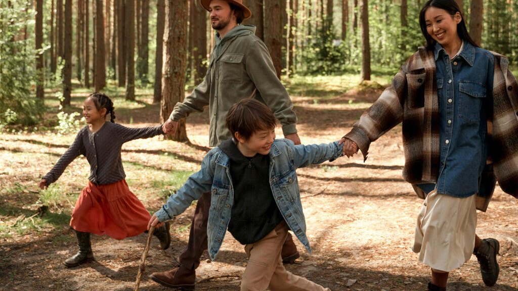 A family — kids and parents — hiking a wooded trail together